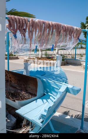 Octopus hängen draußen in der Sonne zu trocknen, wo es auf einem Grill in der Stadt Skala auf der kleinen griechischen Insel Agistri, Saronischer Golf, Griechenland gekocht wird Stockfoto