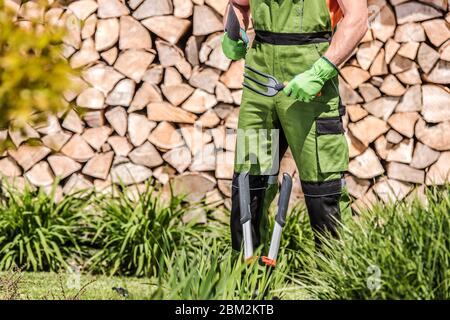 Kaukasische Männliche Erdwächter Stehen In Yard Holding Gartenarbeit Handwerkzeuge Erste Bereit Für Die Arbeit. Stockfoto