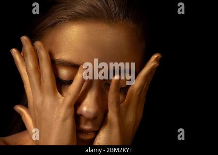 Gesicht der goldenen Frau Nahaufnahme. Ein schönes Mädchen in einer goldenen Maske auf ihrem Gesicht. Beauty Concept.futuristisches, vergoldetes Make-up. Lackierte Haut. Stockfoto