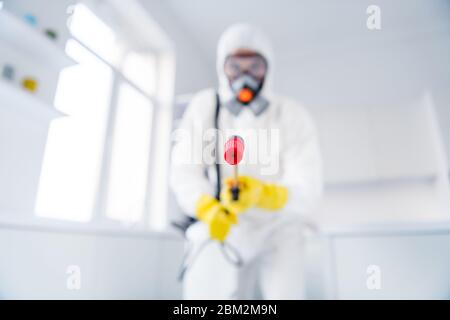 Verschwommenes Low-Winkel-Ansicht Foto von Sprayer Cleaner halten Latex Handschuhe Schutzbrille Overall Spray desinfizieren Oberfläche zu stoppen Verbreitung ncov-Epidemie im Haus Stockfoto