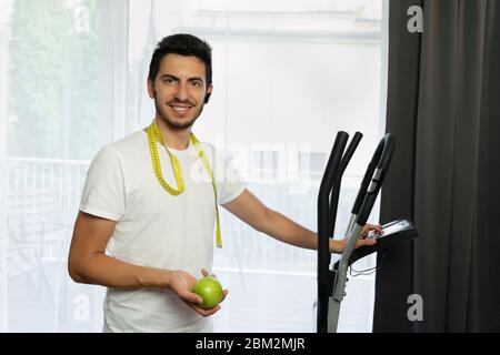 Ein Mann geht in Quarantäne zu Hause zum Sport. Ein junger Mann wird auf einem Simulator engagiert, ohne nach draußen zu gehen. Stockfoto