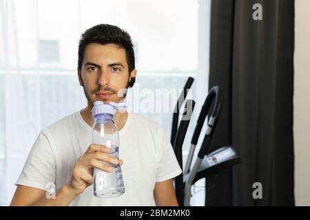 Ein Mann geht in Quarantäne zu Hause zum Sport. Ein junger Mann wird auf einem Simulator engagiert, ohne nach draußen zu gehen. Stockfoto