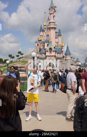 Mädchen macht ein Bild von einem jungen Mann im Park mit Märchenschwanz Burg im Hintergrund und in der Mitte der Menge der Besucher. Paris Frankreich, 29. Mai 201 Stockfoto