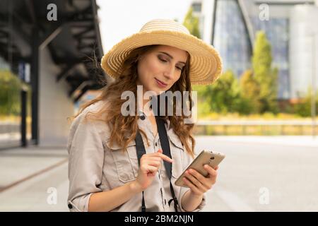 Bild von aufgeregt junge hübsche Frau Tourist posiert. Eine Frau mit einem Koffer steht am Bahnhof, sie kommuniziert mit jemandem am Telefon. Stockfoto