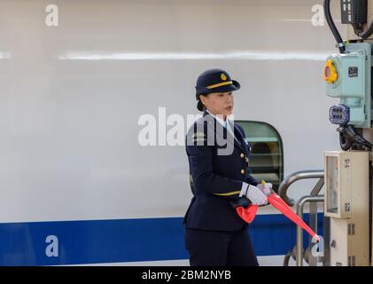 Osaka / Japan - 20. Dezember 2017: Weiblicher Bahnhofsmitarbeiter der Central Japan Railway Company vor dem shinkansen-Hochgeschwindigkeitszug bei Shin Stockfoto