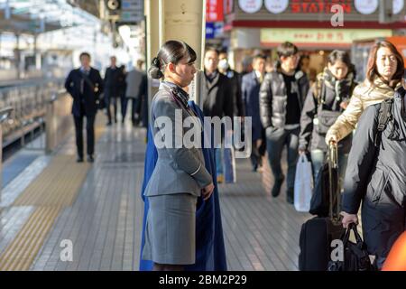 Osaka / Japan - 20. Dezember 2017: Weibliche Zugbegleiterin steht am Bahnhof Shin-Osaka, während Passagiere in der Schlange warten, um an Bord des Sh Stockfoto