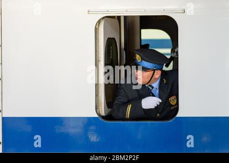 Osaka / Japan - 20. Dezember 2017: Japanischer Zugfahrer schaut durch das Fenster und überprüft, ob alle Passagiere an Bord des shinkansen-Büles sind Stockfoto