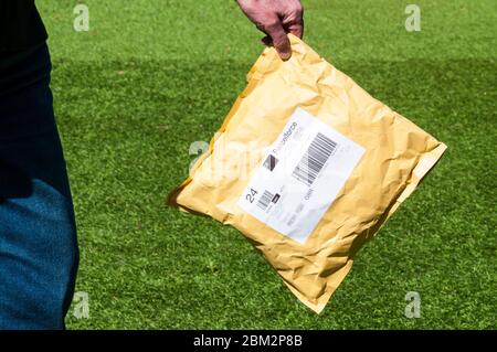Frau, die während der COVID-19-Coronavirus-Pandemie 2020 eine Paketzustellung sehr sorgfältig hält. Stockfoto