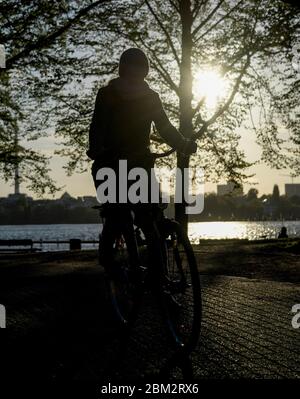 Hamburg, Deutschland. Mai 2020. Ein Radfahrer fährt in der Abendsonne am Ufer der Außenalster entlang. Quelle: Axel Heimken/dpa/Alamy Live News Stockfoto