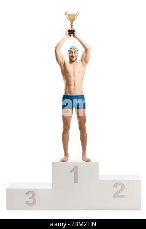 In voller Länge Porträt eines männlichen Schwimmerin hob einen goldenen Pokal auf einem Siegerpodest isoliert auf weißem Hintergrund Stockfoto