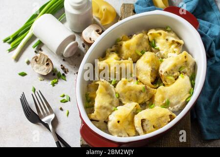 Italienische Pasta Conchiglioni Rigati gefüllt mit Huhn, königliche Champignons, gebacken mit Käse in Bechamel-Sauce auf einer grauen Steinplatte. Stockfoto