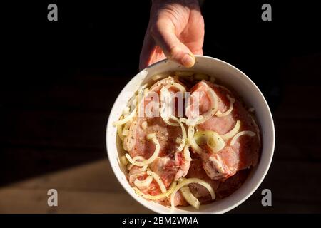 Rohes Rindfleisch Fleisch in Marinade. Rohes Fleisch Schweinefleisch oder Rindfleisch in einem Teller in männlicher Hand, Vorbereitung gesunder Lebensmittel, Marinade und Gewürze Paprika, Menü Konzept Hintergrund Stockfoto