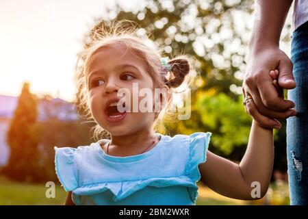 Motehr's Day. Glücklich kleines Kleinkind Mädchen lachen und schreien im Freien. Mutter hält Tochter Hand im Park. Stockfoto