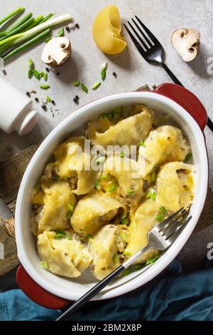 Italienische Pasta Conchiglioni Rigati gefüllt mit Huhn, königliche Champignons, gebacken mit Käse in Bechamel-Sauce auf einer grauen Steinplatte. Draufsicht fl Stockfoto