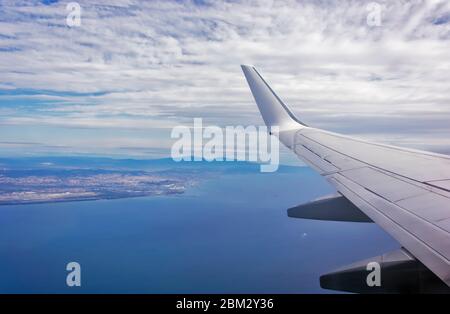 Ansicht des Flügels von einem Flugzeug über den Wolken in großer Höhe fliegen unter einem blauen Himmel durch das Fenster auf der Beifahrerseite. Im Flug über Europa. Anzeigen von je Stockfoto