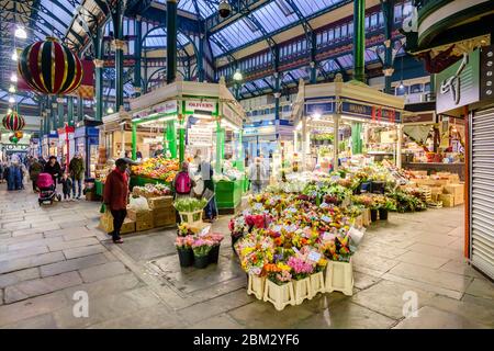 Innenansicht des Leeds Kirkgate Indoor Market, der Blumen-/Gemüsestände und die viktorianische Architektur mit dem Glasdach zeigt Stockfoto