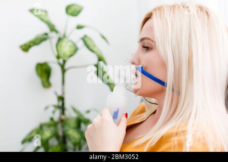 Krank schöne weibliche hält Nasenmaske mit Atembeschwerden im Krankenhauszimmer. Frau Patient Inhalationstherapie durch die Maske von Inhalator mit weich Stockfoto