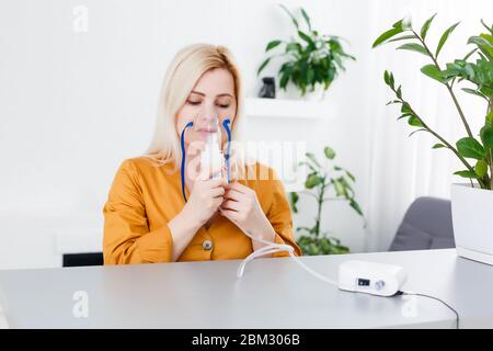 Krank schöne weibliche hält Nasenmaske mit Atembeschwerden im Krankenhauszimmer. Frau Patient Inhalationstherapie durch die Maske von Inhalator mit weich Stockfoto