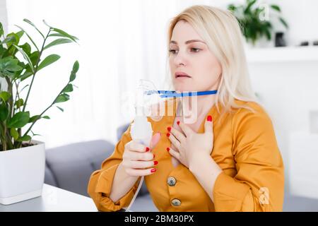 Krank schöne weibliche hält Nasenmaske mit Atembeschwerden im Krankenhauszimmer. Frau Patient Inhalationstherapie durch die Maske von Inhalator mit weich Stockfoto