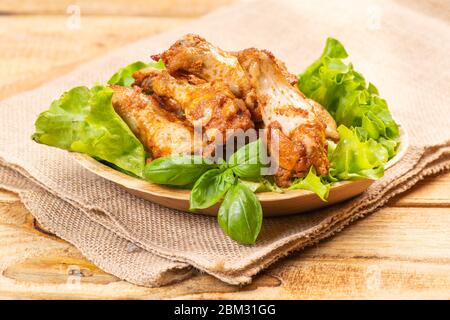 Gebratene Hähnchenflügel in einer Küchenschüssel mit Basilikumblättern und Salat. Fast Food. Stockfoto