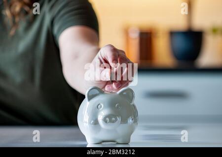 Persönliche Finanzen, Frau, die Geld in ein Sparschwein- -Reichtum und Finanzkonzept. Weißes Sparschwein im Vordergrund. Stockfoto