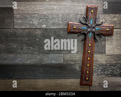 Schönes dekoratives christliches Kreuz mit texanischen Motiven mit Sporen und Cowboy-Gürteln. Konzept der Religion und des Glaubens in den USA Stockfoto