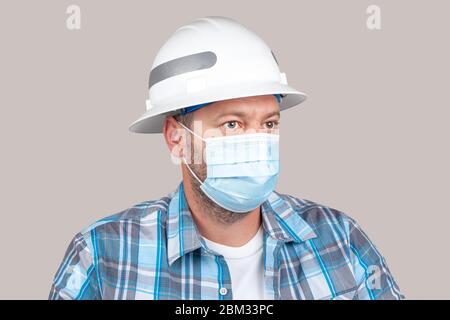 Ingenieur oder Bauarbeiter mit Freizeitkleidung und Sicherheit harten Hut trägt chirurgische Gesichtsmaske. Konzept der neuen Sicherheitsmaßnahmen von Unternehmen Stockfoto