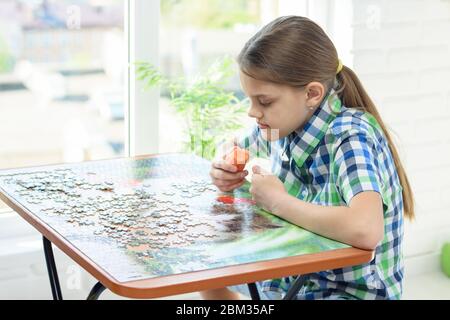 Mädchen zu Hause am Fenster sammelt Rätsel an seinem freien Tag Stockfoto