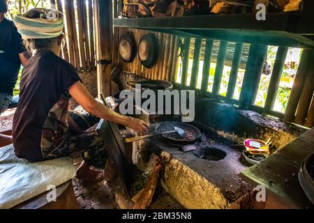 Alte Balinesin, die Kaffeebohnen mit traditioneller Methode röstet Stockfoto