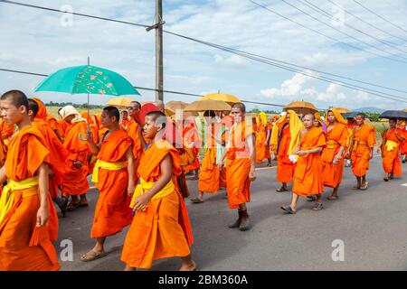 Lokale buddhistische Mönche in traditionellen Safranfarben gehen entlang einer Straße außerhalb von Chiang Rai, einer Stadt im Norden Thailands Stockfoto