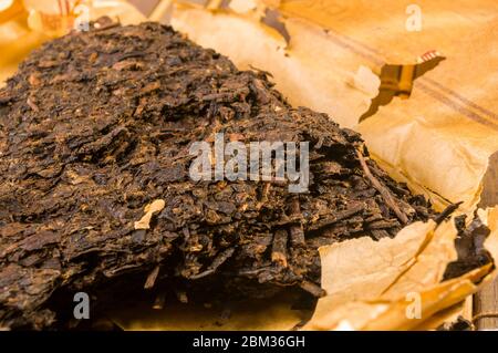 Chinesisch drückte PU-ERH Tee auf Wickelpapier und Teemesser, Nahaufnahme Stockfoto