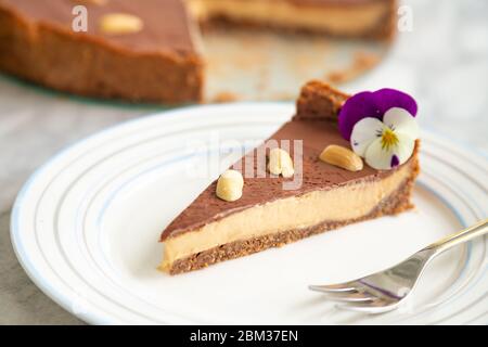 Scheibe rohe hausgemachte vegane Erdnussbutter Mousse Kuchen mit Walnüssen und Datteln Kruste Stockfoto