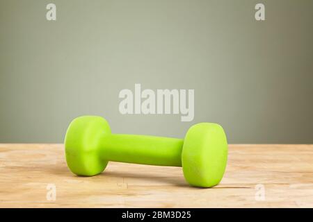 Grüne Hanteln auf dem Holztisch mit Kopierfläche. Stockfoto