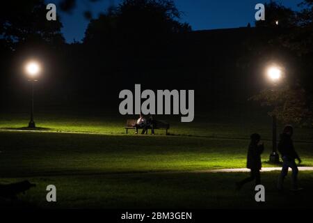 Zwei Personen sitzen nach Sonnenuntergang auf einer Bank auf Primrose Hill in London. Stockfoto