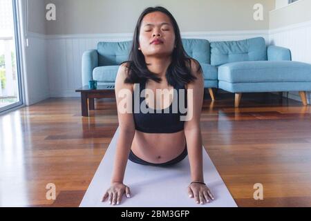 Junge Frau macht Yoga auf Yoga-Matte zu Hause Stockfoto