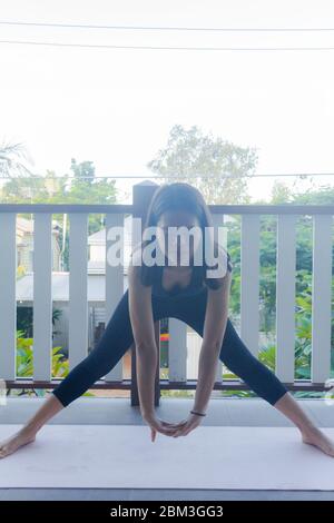 Junge Frau macht Yoga auf Yoga-Matte zu Hause Stockfoto