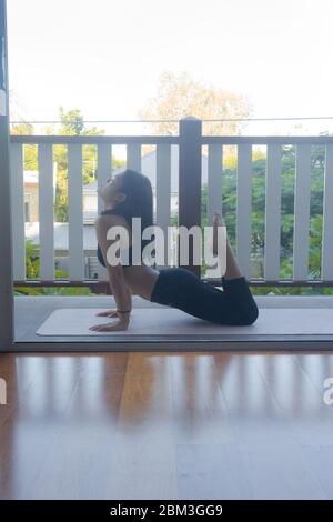 Junge Frau macht Yoga auf Yoga-Matte zu Hause Stockfoto