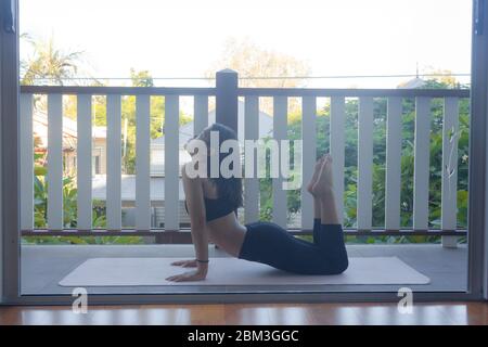 Junge Frau macht Yoga auf Yoga-Matte zu Hause Stockfoto