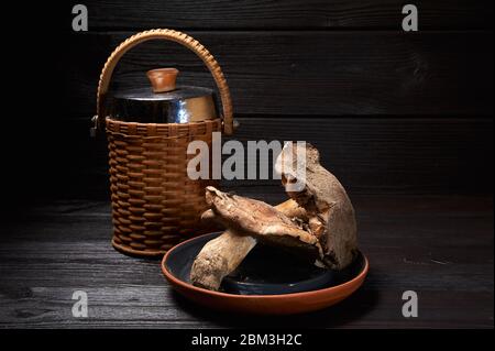 Stillleben von Pilzen auf schwarzem Holzhintergrund und einem Retro-Krug Milch Stockfoto