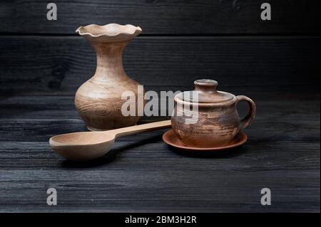 Steingut im ethnischen Stil auf schwarzem Holzhintergrund mit einer hölzernen Schöpfkelle Stockfoto