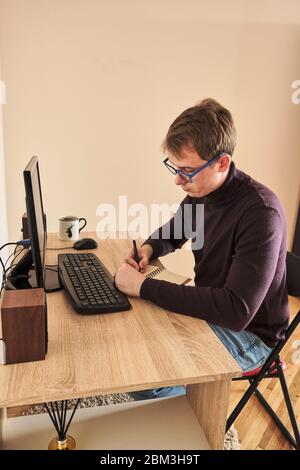 Lächelnd Mann bei der Arbeit am Computer am Schreibtisch im Büro Stockfoto