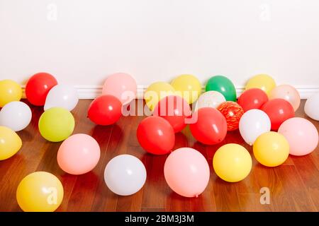 Gruppe von vielen bunten Luftballons, die auf dem Boden in der Studiowohnung liegen. Dekoration Interieur für Geburtstagsfeier. Festlicher Hintergrund Stockfoto