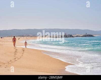 Frauen, die am Sommermorgen am Strand von Nazaré in Portugal spazieren Stockfoto