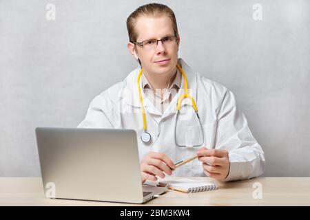 Telemedizin Konzept Arzt Mann sitzt an einem Tisch mit einem Laptop. Nahaufnahme. Stockfoto