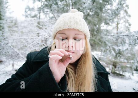 Junge Frau raucht an einem Wintertag eine Marihuana-Zigarette Stockfoto