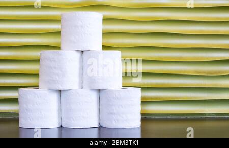 6 Rollen Toilettenpapier in Pyramidenform vor einem goldenen Hintergrund mit Kopierfläche gestapelt Stockfoto