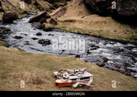 Ein improvisiertes Hochzeitstisch für zwei Personen am Ufer des Berges, auf dem Gras in Island. Ein Tisch aus Baupalette mit Treibholz und dekoriert Stockfoto