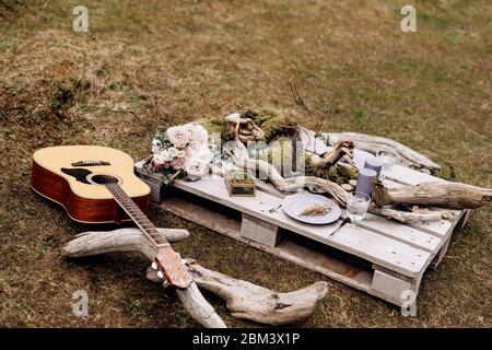 Ein improvisiertes Hochzeitstisch für zwei Personen am Ufer des Berges, auf dem Gras in Island. Ein Tisch aus Baupalette mit Treibholz und dekoriert Stockfoto