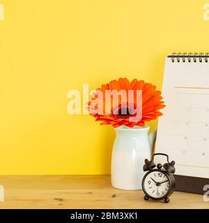 Kalender und Wecker auf Tisch mit gelbem Hintergrund. Geschäftsplan und Zeitkonzept Stockfoto