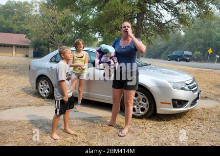 Bastrop County Texas, USA, 6. September 2011: Atta Wiley (r) und ihre beiden Kinder schnappen sich Gegenstände aus ihrem Zuhause, bevor sie die Gegend evakuieren, während sich ein Lauffeuer ihrem Zuhause nähert. Trotz zweitägiger Löschangriffe ist der Brand nach wie vor weitgehend außer Kontrolle. ©Bob Daemmrich Stockfoto